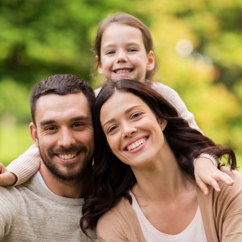 Family of three smiling outdoors