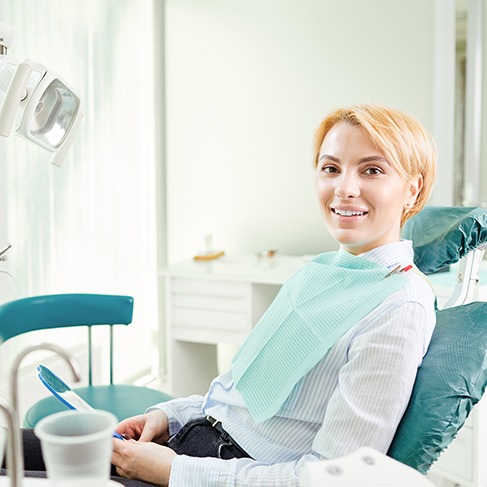 Blonde woman sitting in dental chair and smiling
