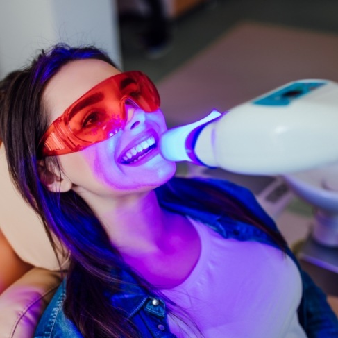 Woman getting professional teeth whitening in dental chair