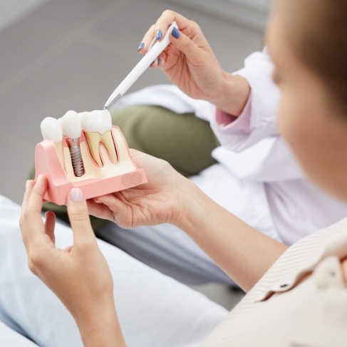 Dentist showing a dental implant model to a patient