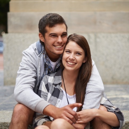 Young man and woman grinning and hugging after visiting Louisville dental office