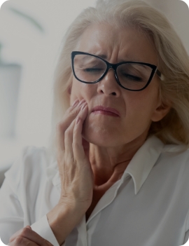 Senior woman wincing and holding her cheek in pain