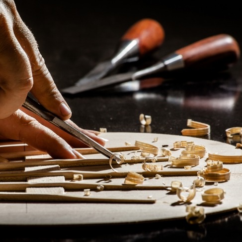 Person carving several small wooden sticks
