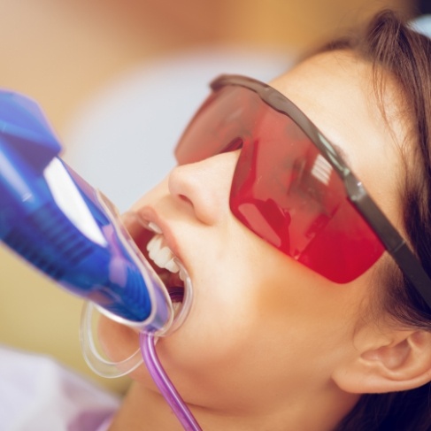 Young woman in dental chair with fluoride trays on her teeth