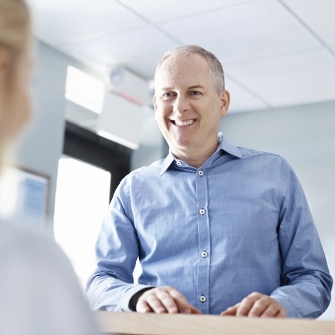 Man smiling at receptionist in Louisville dental office