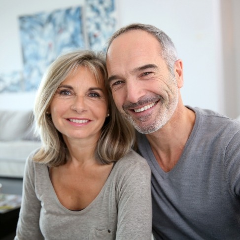 Older man and woman smiling after restorative dentistry in Louisville