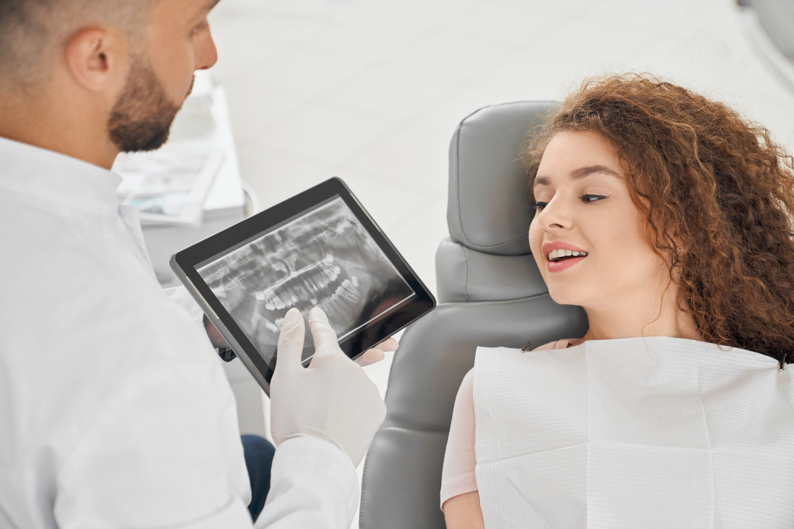 Skilled male dentist showing x ray picture of teeth to woman